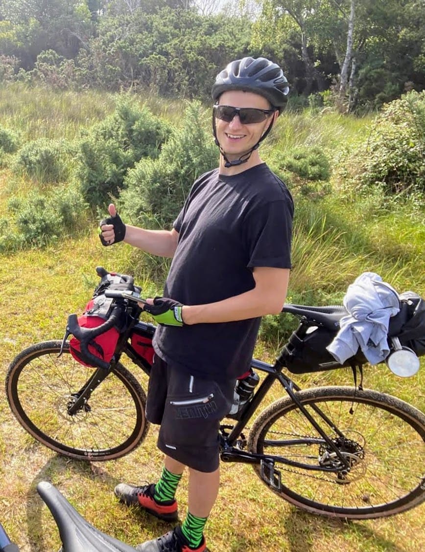 That's me on my bike, loaded with bikepacking bags, standing in the garden with palm trees in the background.